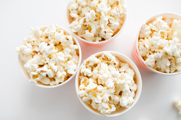 fast food, junk-food and unhealthy eating concept - close up of popcorn in disposable paper cups from top