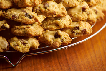 Stack of cookies on a metal cooling grid placed on a wooden surface with black background 