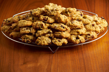 Stack of cookies on a metal cooling grid placed on a wooden surface with black background 