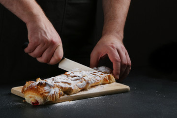 chef slices a pie on dark background. pie making concept. recipe of pie or cake
