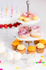 party food and festive concept - different sweets on stand and birthday cake