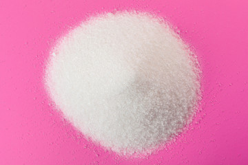 White sugar on a pink background top view