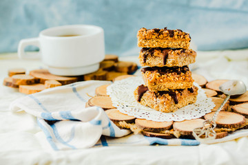 Organic homemade granola bars with salt date caramel and chocolate on blue background.Selective focus.A cup of coffee. Healthy breakfast.