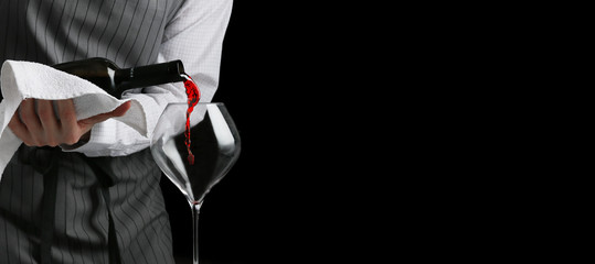 bartender pours wine in glass baner on dark background