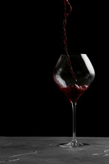 red wine pouring in wine isolated on black