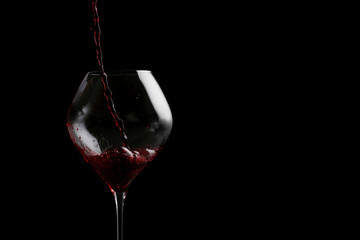 red wine pouring in wine isolated on black