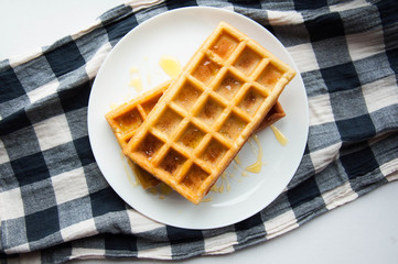 Belgian waffles on a white plate on the table. French or American breakfast. Vintage style. Sweet food.