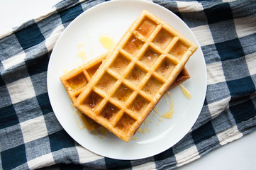 Belgian waffles on a white plate on the table. French or American breakfast. Vintage style. Sweet food.