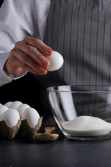 breaks the egg for dough. recipe pie or cake making concept on dark background