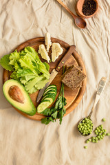 Ingredients for green salad with a piece of bread. Make a fresh salad of avocado, greens, peas, parsley, cabbage, cucumber and apples.Vegetables on a wooden board. Top view.