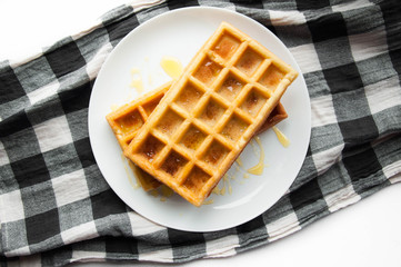 Belgian waffles on a white plate on the table. French or American breakfast. Vintage style. Sweet food.