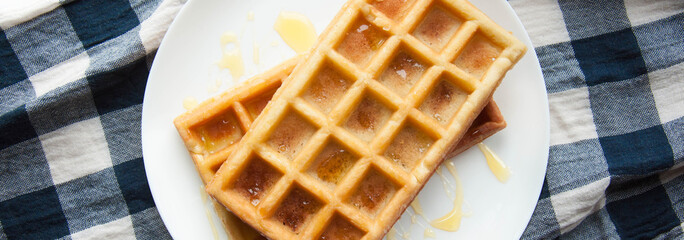 Belgian waffles on a white plate on the table. French or American breakfast. Vintage style. Sweet food.