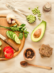 Ingredients for green salad with a piece of bread. Make a fresh salad of avocado, greens, peas, parsley, cabbage, cucumber and apples.Vegetables on a wooden board. Top view.