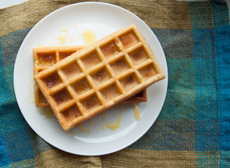 Belgian waffles on a white plate on the table. French or American breakfast. Vintage style. Sweet food.