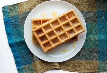 Belgian waffles on a white plate on the table. French or American breakfast. Vintage style. Sweet food.