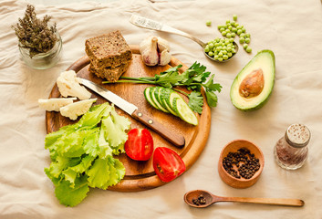 Ingredients for green salad with a piece of bread. Make a fresh salad of avocado, greens, peas, parsley, cabbage, cucumber and apples.Vegetables on a wooden board. Top view.