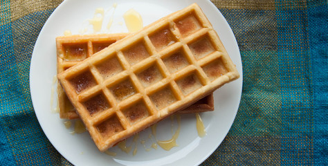 Belgian waffles on a white plate on the table. French or American breakfast. Vintage style. Sweet food.