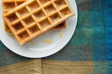 Belgian waffles on a white plate on the table. French or American breakfast. Vintage style. Sweet...