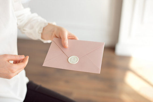 Close-up of woman in white shirt of business style holds in her hand a invitation card, card, letter