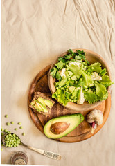 Fresh delicious green salad with avocado in a wooden plate and gluten free toast. Top view. Healthy lunch dish and Diet detox food concept.
