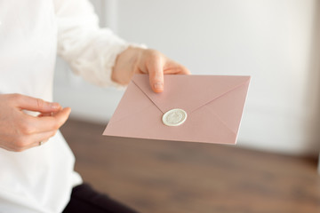 Close-up of woman in white shirt of business style holds in her hand a invitation card, card, letter