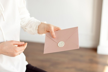 Close-up of woman in white shirt of business style holds in her hand a invitation card, card, letter