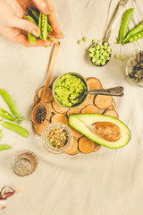 Sauce with avocado (guacamole), with sweet green peas in a metal container.. Hands of a young woman. Toning