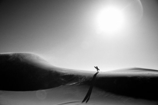 Frau mit Surfboard auf Düne