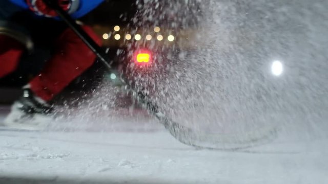 Close-up slow motion hockey puck and flying snow on the ice , hockey player picks up the puck stick