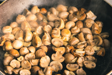 Champignon mushrooms are fried in a pan - close-up