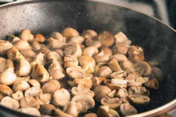 Champignon mushrooms are fried in a pan - close-up