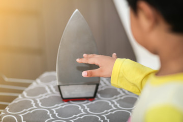 A young boy hand touches iron hot sole plate. 