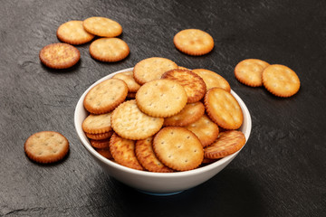 A photo of salt crackers in a bowl on a dark background with copy space