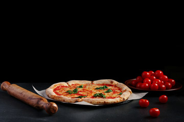 izza margarita with tomatoes and ingredients on dark stone background with copy space