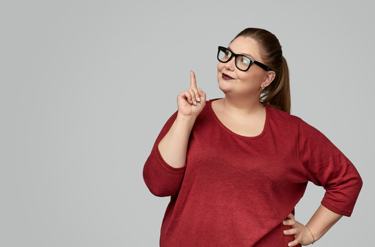 Confident plump woman pointing up
