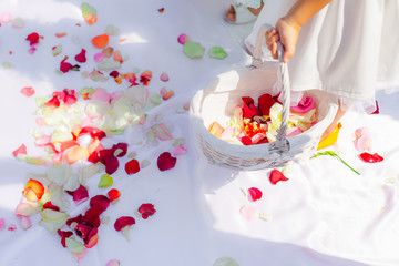 Close-up of a small girl's hand with a basket of petals of roses