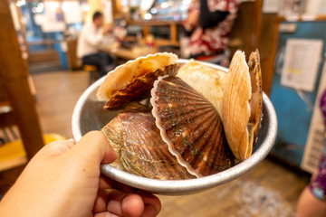 close up Fresh Japanese Scallops or Hotate with Shells in bowl on my hand.