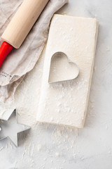 Raw puff pastry dough lies on a white table. Figures for baking cut metal mold. Copy space, top view.