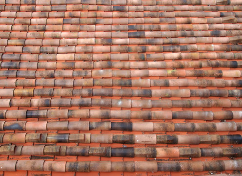 full frame image of an oldclay pantile roof with curves orange tiles in long rows
