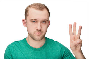 Fototapeta premium A funny young man in a green shirt shows three two