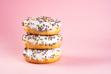 Donuts with icing on pastel pink background. Sweet donuts. Copy space.