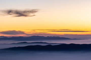 Beautifully colored sky at dusk, with mountains layers and mist between them