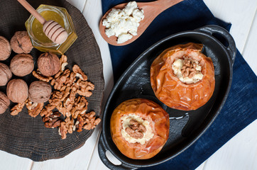 healthy food. Baked apples with cottage cheese and nuts lie in a black baking dish on a black wooden table
