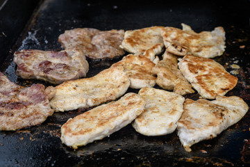Bunch of different pieces of meat cooking a hot grill at a street food market