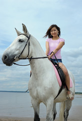 Obraz premium Young pretty asian woman riding white horse