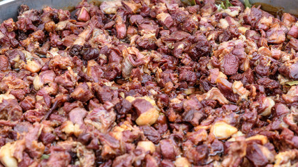 Large group of pieces of different cubes of fried meat in soft focus, at a street food market 