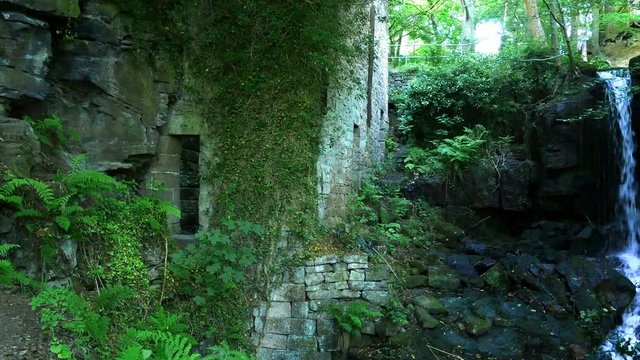 Romantic stone ruins of the 17th century grinding mill with waterfall. Lumsdale, Derbyshire, England.