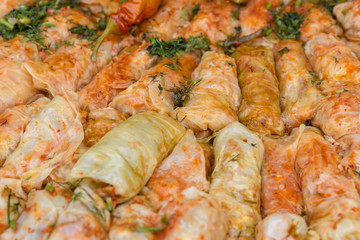 Close up of a freshly cooked large portion of sarmale, traditional Romanian cabbage rolls, with hot pepper and dill in display at a food market