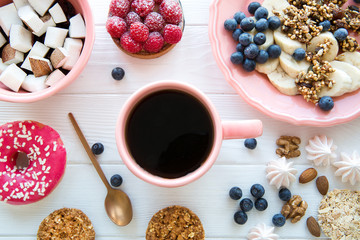Stylish served table with healthy organic food, tasty doughnut and raspberry cake. Banana and coconut pieces, granola and little merengue. Pink and coral living color plate and cup. 