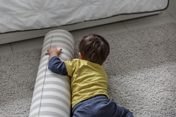 A cute blond boy plays and enjoys on the carpet in his bedroom